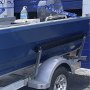 blaues Boot auf einem Anhänger, ausgestattet mit VEVOR-Bootsanhänger-Führungen auf einem Parkplatz.