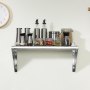 Estante de acero inoxidable VEVOR con frascos, recipientes y botellas en una pared de cocina beige debajo de un reloj.