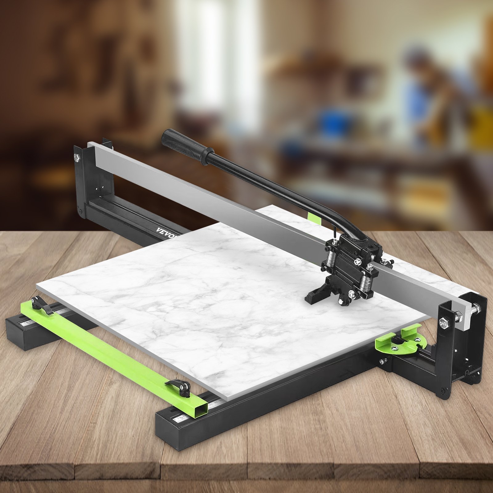 Cortadora de azulejos VEVOR sobre mesa de madera con azulejos de mármol, mango negro y detalles verdes.