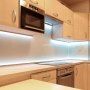 Cocina moderna con gabinetes de madera clara, electrodomésticos de acero inoxidable y luces LED VEVOR en el escaparate.