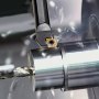 Portaherramientas de torneado de torno VEVOR que mecaniza un cilindro de metal con virutas de corte despedidas.