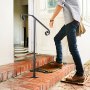 Hombre que usa pasamanos VEVOR en escalones de ladrillo para entrar a una casa.