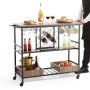 Carrito de bar VEVOR negro lleno de vino, copas, comida y bebidas, junto a él hay un hombre con delantal negro.