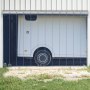 Cortina de tiras VEVOR instalada en la entrada de un almacén con un camión estacionado parcialmente visible detrás de ella.