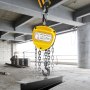 Polipasto de cadena VEVOR elevando una viga de acero en un edificio en construcción.