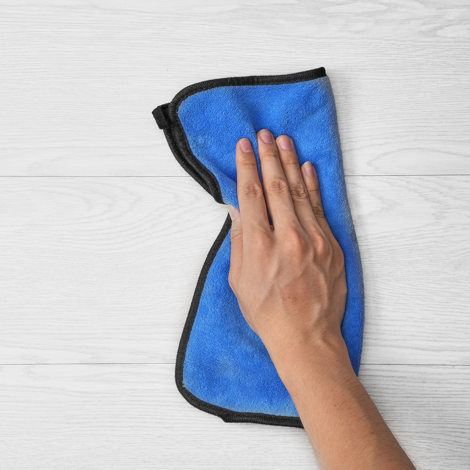 Limpieza a mano de baldosas de vinilo VEVOR con un paño azul sobre suelo de madera clara.