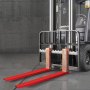Extensiones de horquillas para paletas VEVOR rojas en una carretilla elevadora en un almacén industrial gris.