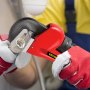 Manos usando una llave de tubo roja VEVOR para apretar un accesorio de tubería de metal.