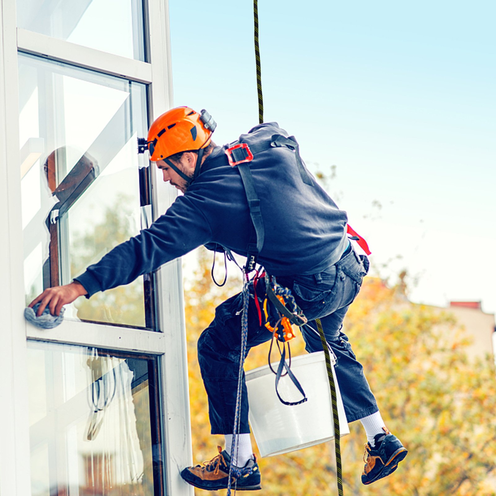 Limpiador de ventanas que utiliza cuerda de protección contra caídas VEVOR y casco naranja para mayor seguridad.