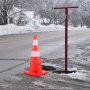 Conos de seguridad VEVOR en una calle helada junto a un poste rojo y montones de nieve.