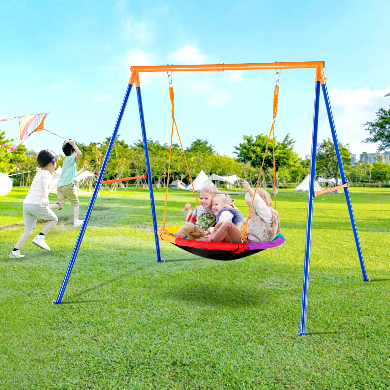 Niños disfrutando de un columpio VEVOR en un parque soleado, con otros niños volando una cometa en el fondo.