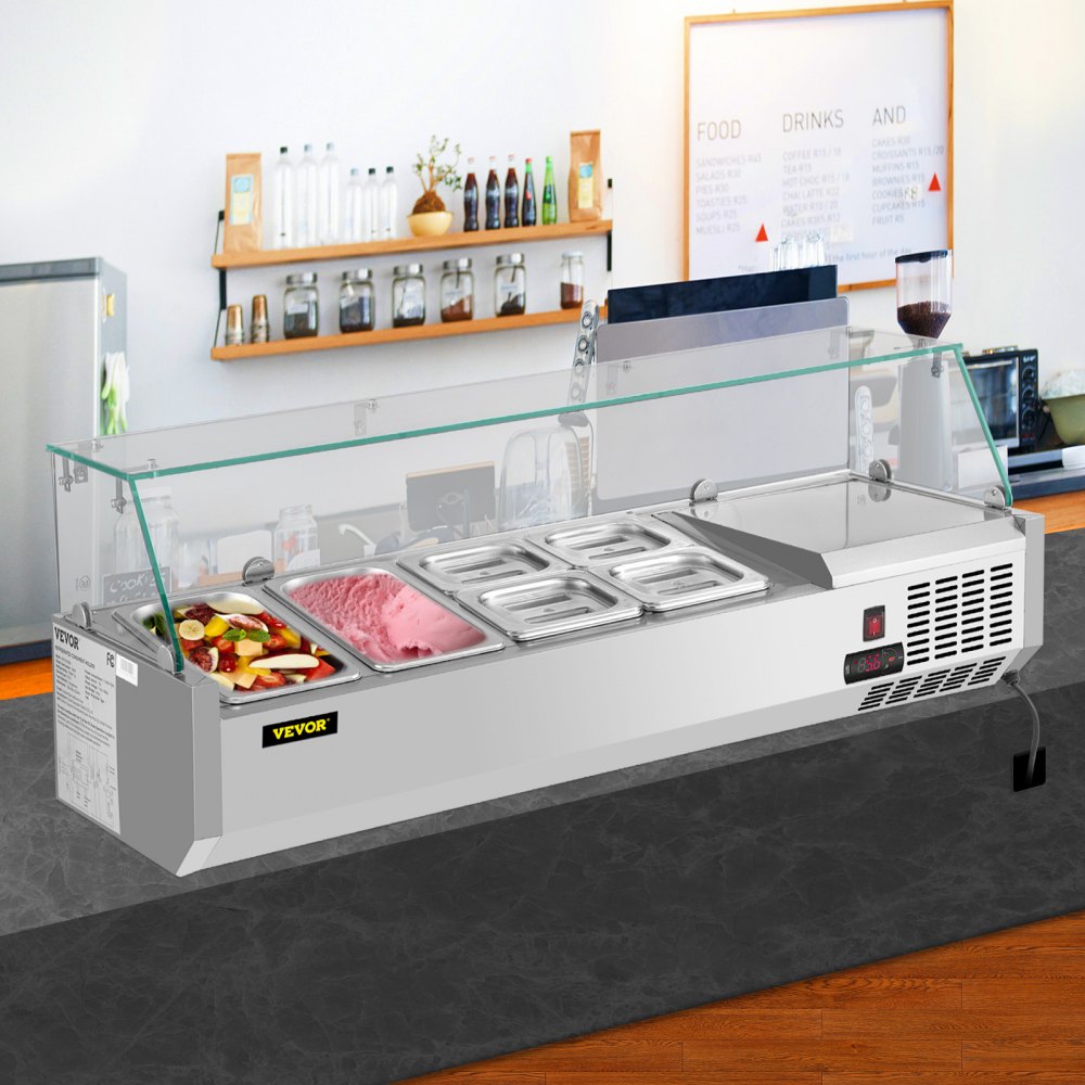 Estación de preparación refrigerada VEVOR con protector de vidrio contra estornudos, llena de alimentos variados en una cocina moderna.