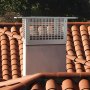 Chimenea VEVOR sobre tejado de tejas con árboles al fondo.