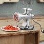 Picadora de carne manual VEVOR procesando pimientos rojos en una encimera de cocina de madera.