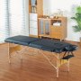 Mesa de masaje portátil VEVOR negra en una habitación acogedora y soleada con suelos de madera y muebles modernos.