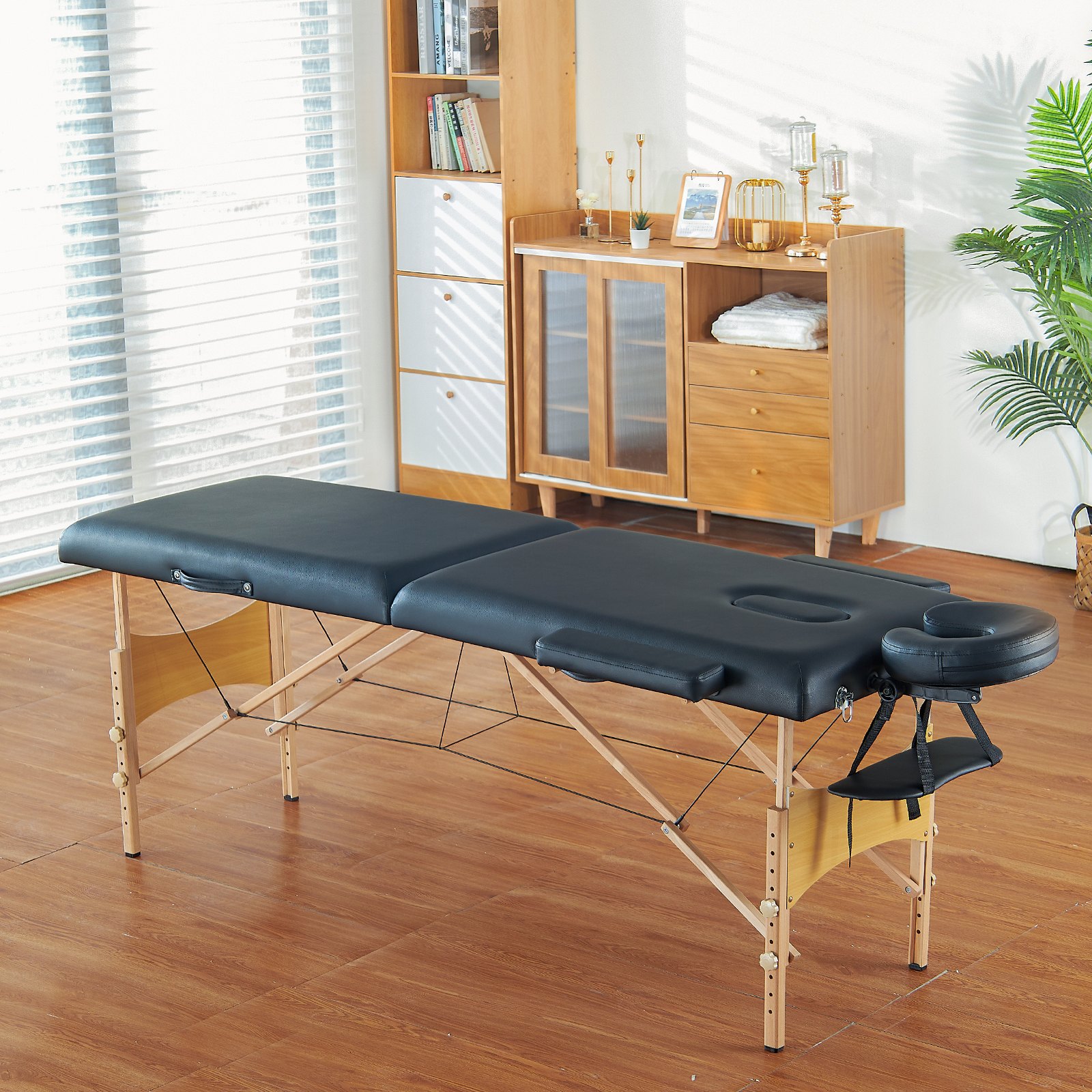 Mesa de masaje portátil VEVOR negra en una habitación acogedora y soleada con suelos de madera y muebles modernos.