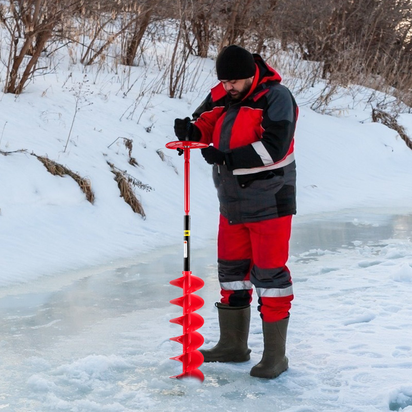 Persona que utiliza la barrena perforadora de hielo VEVOR en un lago congelado en invierno.
