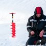 Taladro de hielo VEVOR en un paisaje nevado con una persona pescando en el hielo cerca.