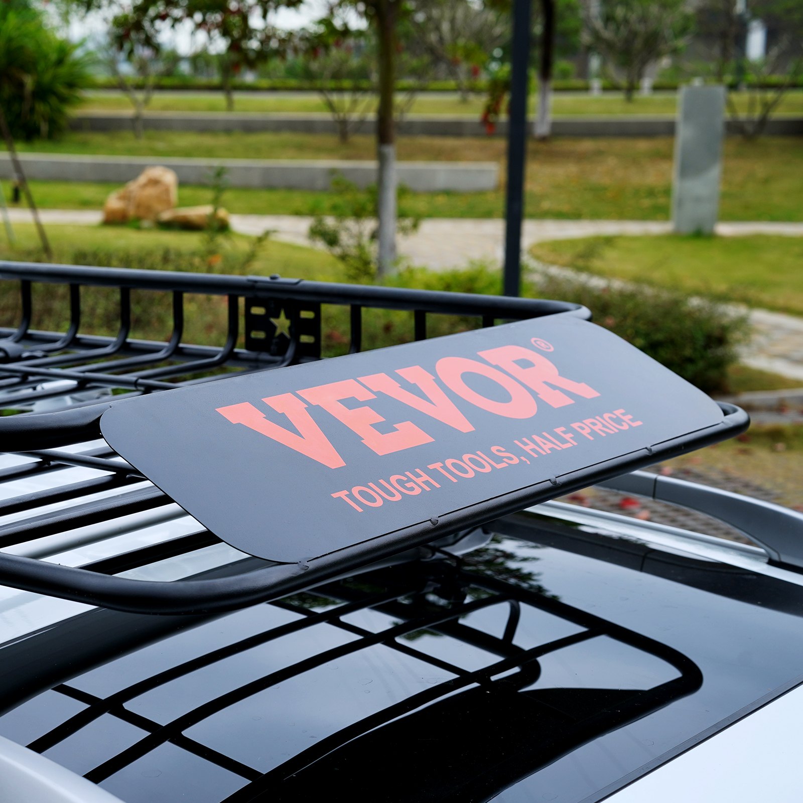 Cesta de carga para portaequipajes de techo VEVOR en un vehículo, que muestra el logotipo de la marca en un entorno pintoresco al aire libre.