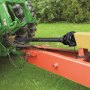 Eje de toma de fuerza VEVOR conectado a un tractor verde y maquinaria roja en un patio cubierto de césped.
