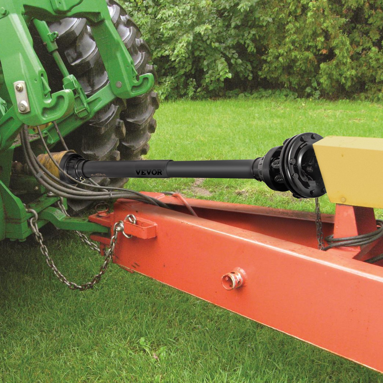 Eje de toma de fuerza VEVOR conectado a un tractor verde y maquinaria roja en un patio cubierto de césped.