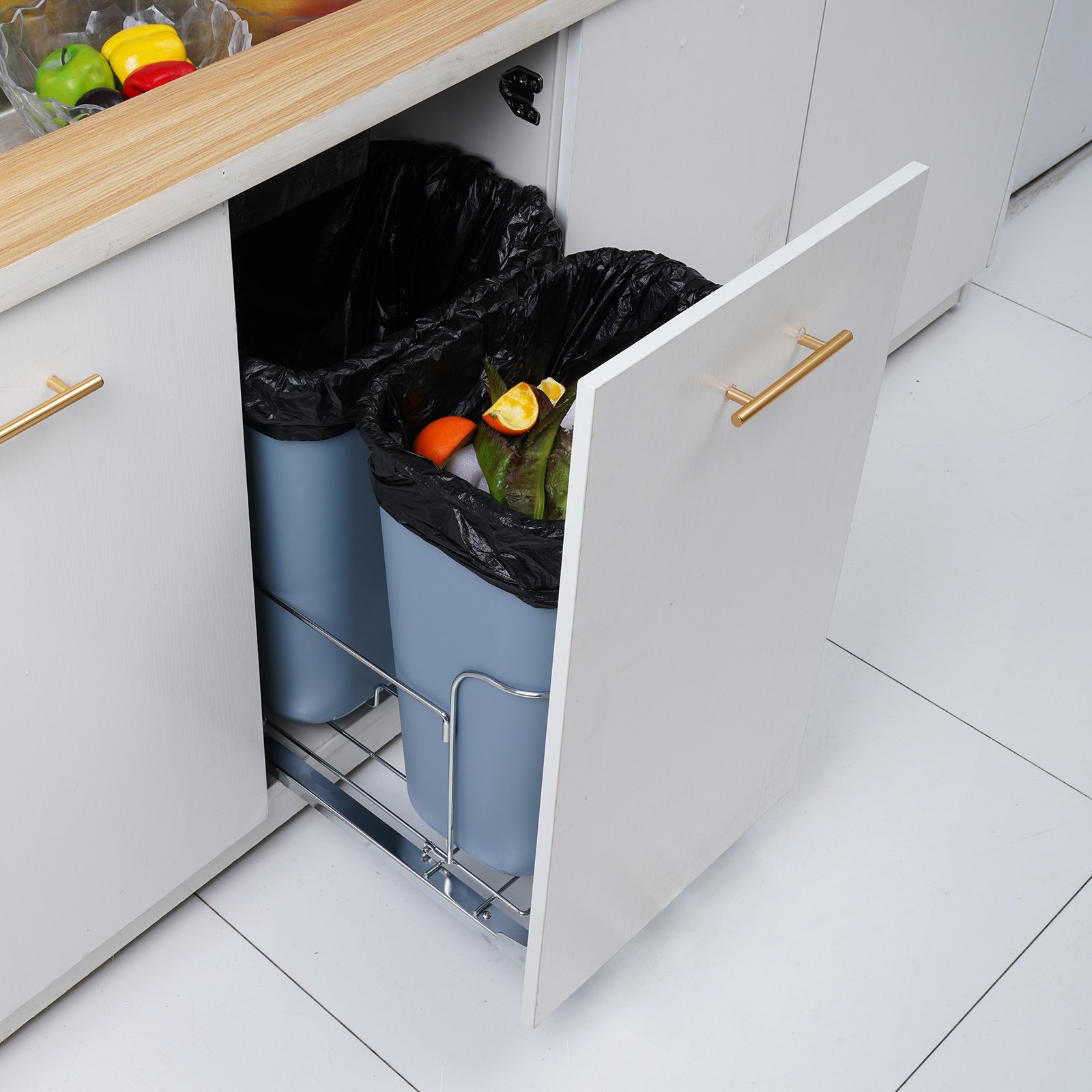 Bote de basura extraíble VEVOR debajo del fregadero con compartimentos dobles y frutas en la encimera.