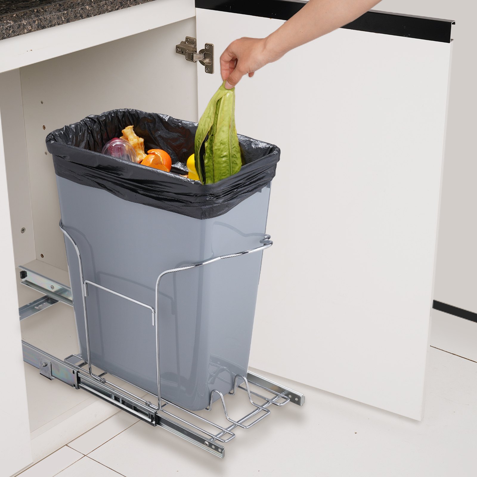 Mano colocando desechos de comida en un bote de basura extraíble VEVOR en un armario de cocina.