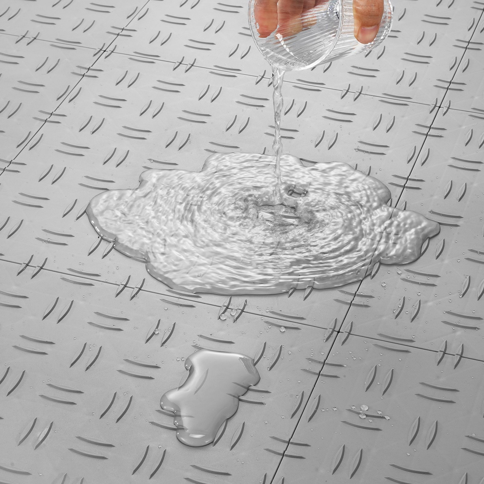 Agua vertida sobre baldosas de garaje antideslizantes VEVOR, demostrando un excelente drenaje y durabilidad.
