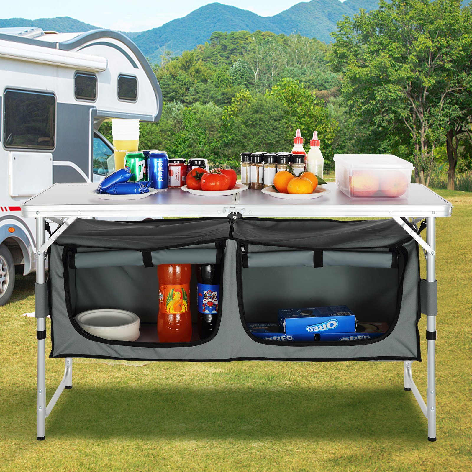 Mesa de camping VEVOR instalada en el exterior de una casa rodante con comida, bebidas y bocadillos organizados encima y debajo de ella.