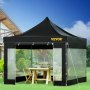 Carpa plegable VEVOR en un jardín con árboles, sillas y una mesa para cenar.