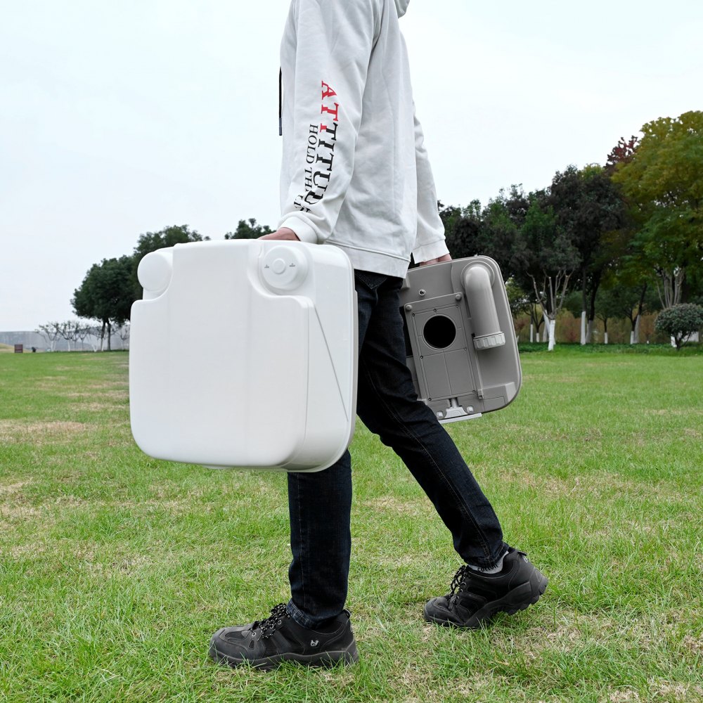 Persona que transporta un baño portátil VEVOR en un parque, mostrando la facilidad de transporte.