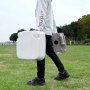 Persona que transporta un baño portátil VEVOR en un parque, mostrando la facilidad de transporte.