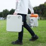 Persona que transporta un inodoro portátil para acampar VEVOR en un parque, mostrando su diseño compacto y liviano.