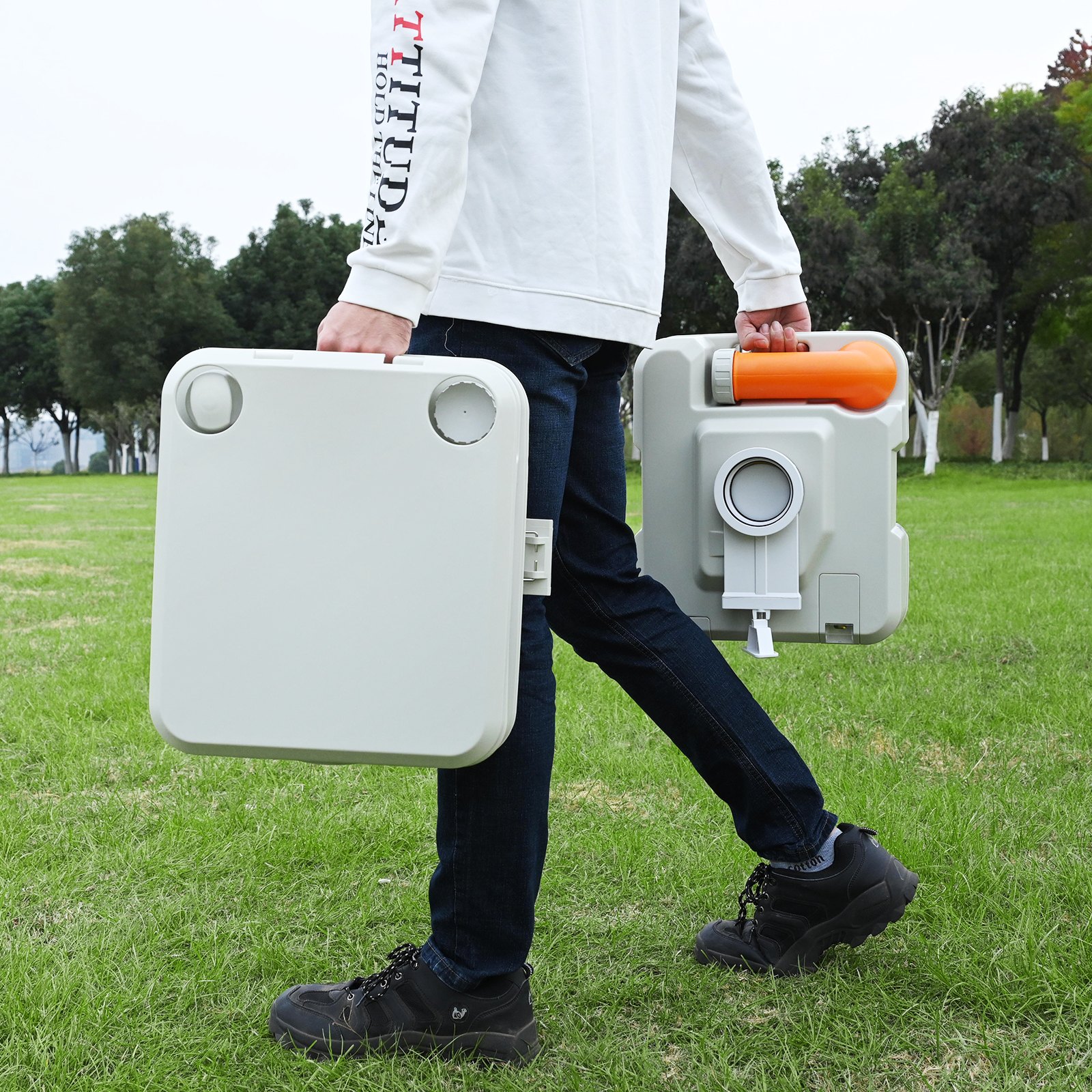 Persona que transporta un inodoro portátil para acampar VEVOR en un parque, mostrando su diseño compacto y liviano.