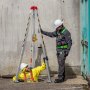 Trabajadores que utilizan el kit de trípode para espacios confinados VEVOR para un descenso seguro en un entorno industrial