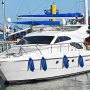 Yate blanco con defensas VEVOR azules atracado en un puerto deportivo.