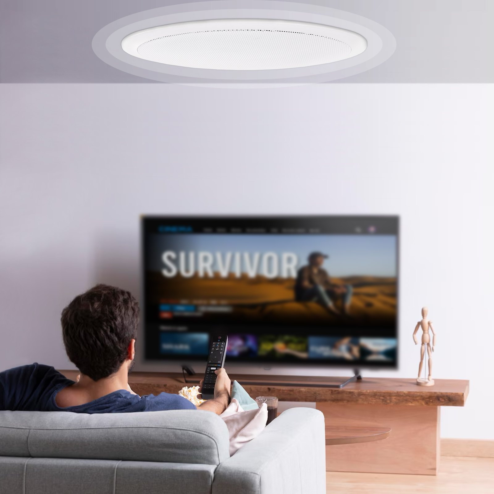Hombre mirando televisión en un sofá con altavoces VEVOR en el techo.