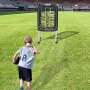 Niño con una camisa gris practicando lanzamiento con la red de entrenamiento de béisbol VEVOR en un campo de césped.
