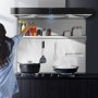 Mujer cocinando con protector contra salpicaduras de la gama VEVOR, mostrando utensilios y especias perfectamente ordenados.