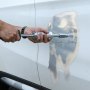 Uso manual del kit de reparación de abolladuras con soldador de pernos VEVOR para arreglar una abolladura en la puerta de un automóvil blanco.