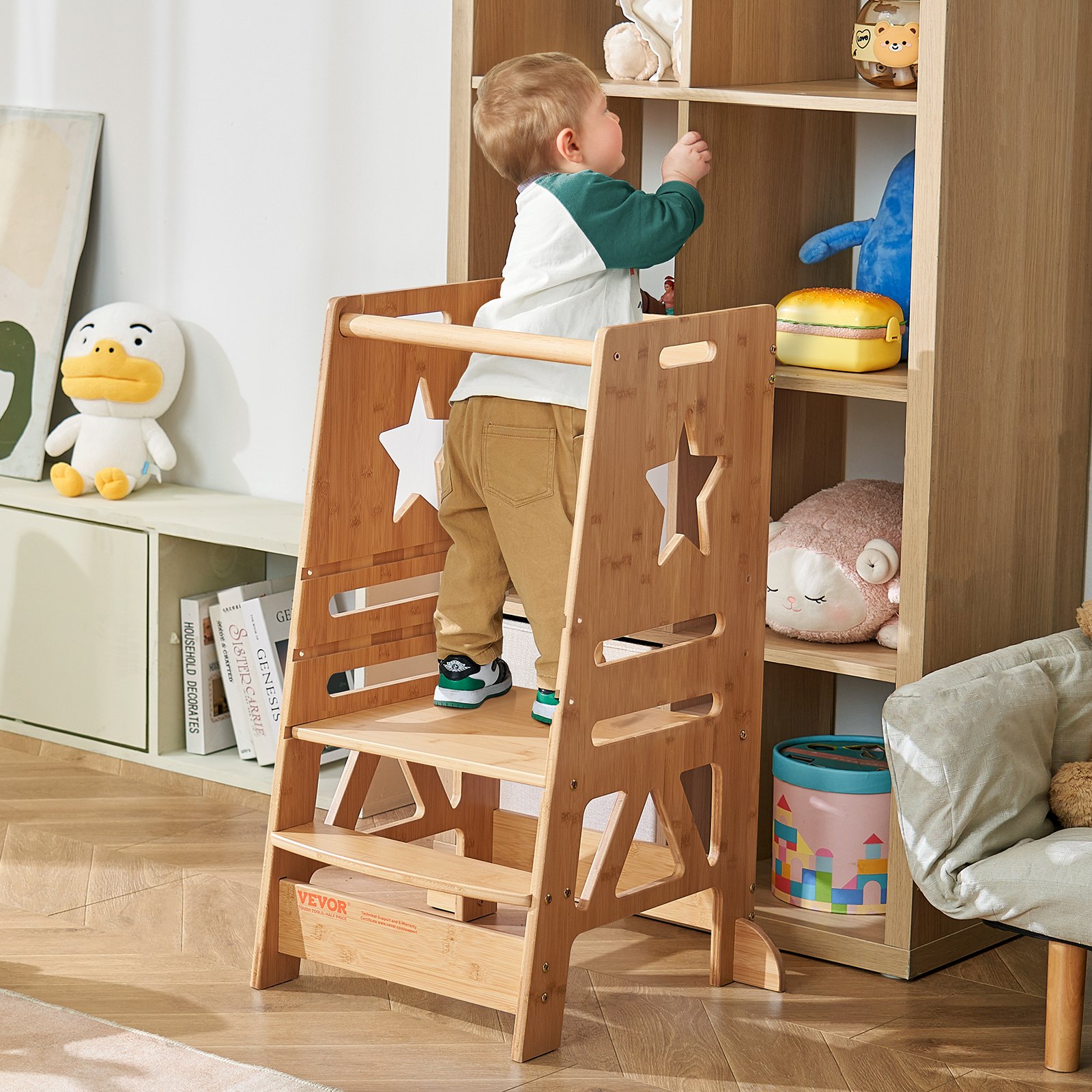 Niño que se levanta de un taburete de torre VEVOR en una habitación acogedora con juguetes de peluche y un estante de madera.