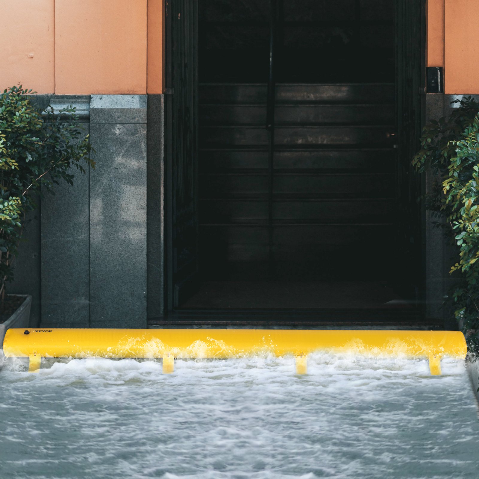 Bolsa antiinundaciones amarilla VEVOR que bloquea el agua en la entrada del edificio, evitando daños por inundación.