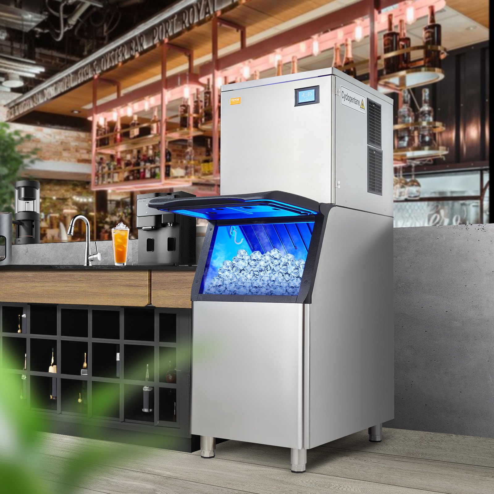 Máquina para fabricar hielo comercial VEVOR en un elegante entorno de bar con depósito de hielo abierto, que muestra la producción de hielo.