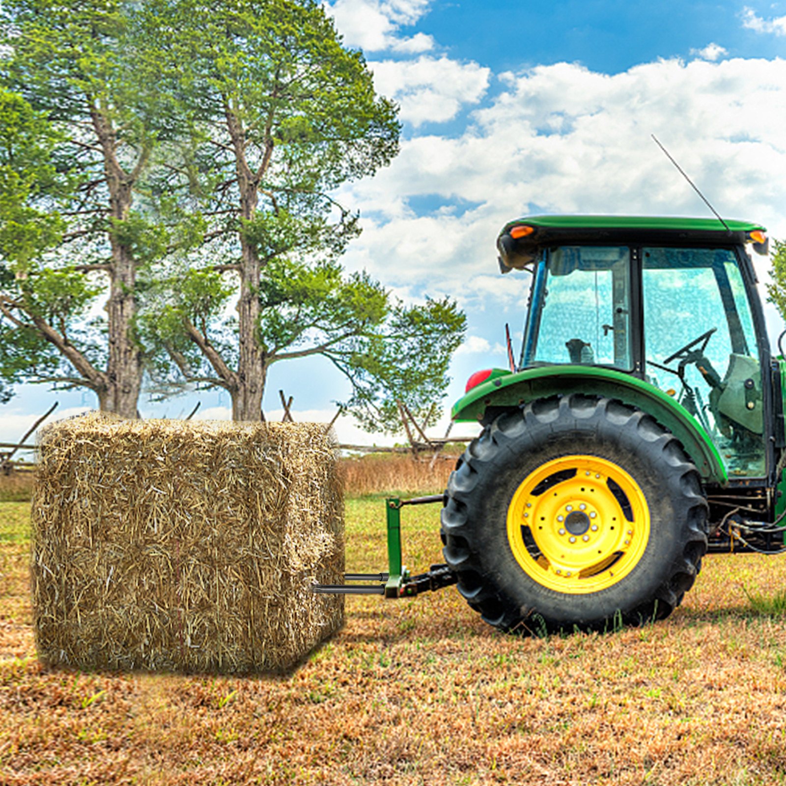 Tractor con lanzas de heno VEVOR levantando un fardo de heno en un campo de hierba con árboles al fondo.