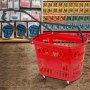 Cesta de compras con ruedas de plástico VEVOR de color rojo en el pasillo de una tienda.