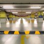 Rampa protectora de cables VEVOR en un estacionamiento subterráneo con marcas de seguridad amarillas.