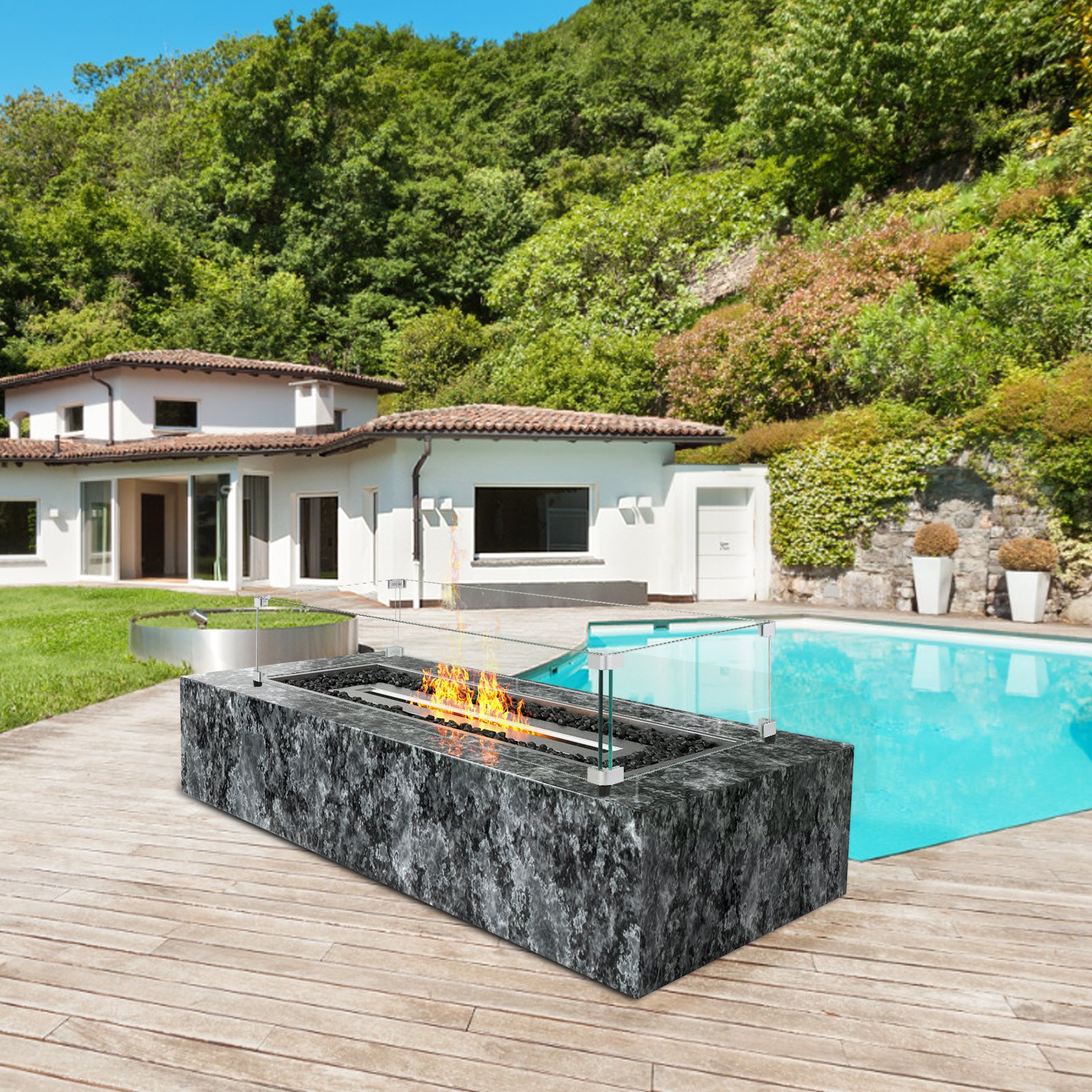 Patio al aire libre con protección contra el viento de vidrio VEVOR alrededor de una fogata cerca de una piscina y una casa moderna.