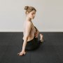 Mujer haciendo yoga sobre colchonetas de gimnasio VEVOR con una camiseta beige claro y pantalones negros, sobre un fondo blanco.