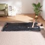 Persona que usa una manta de sauna VEVOR mientras está acostada sobre una alfombra, cerca de un sofá verde, una mesa auxiliar blanca y una planta en maceta.