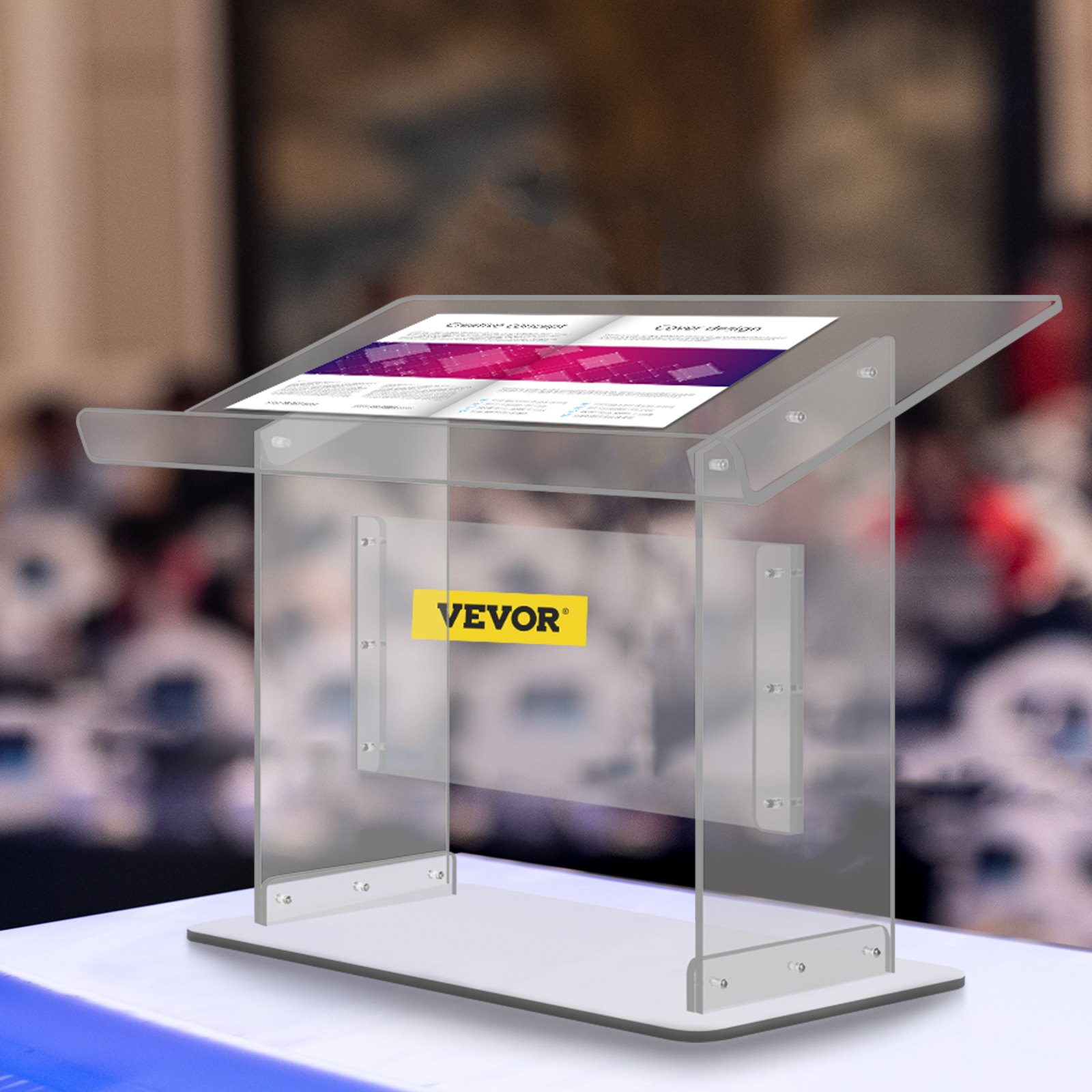 Podio de acrílico VEVOR con diseño transparente, mostrado en un escenario con audiencia borrosa.